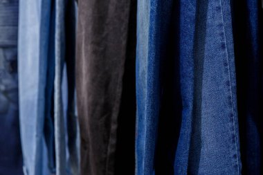 Alışveriş merkezindeki askıların camında asılı bir sürü kot pantolon.