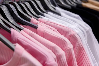 Alışveriş merkezindeki askılarda asılı pembe ve beyaz elbiseler