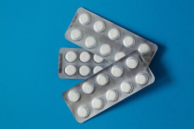 İlaçlar, beyaz haplar mavi arka planda su toplayan paketler yukardan