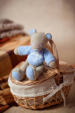 Mavi kazaklı oyuncak ayı ya da fare kahverengi bir sepetin üzerinde oturuyor.