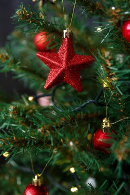 Yılbaşı kartı ve geçmiş. Noel kırmızı oyuncağı bir dalda asılı bir yıldız şeklinde sarı çelenk Bokeh 'in arka planında