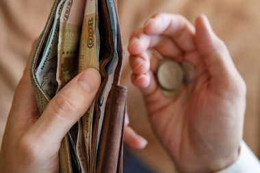 Cüzdanı para ve bozuk paralarla dolu, arka planda hafif monofonik bir adamın elinde. Avucunun içinde dolar banknotları ve sikkeler. Birinci kişi görünümü