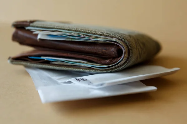 Side view of a wallet with money and a cashier\'s check from the store on a plain light background. Costs of purchases and payment for services.