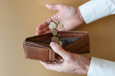 Cüzdanı boş bir adamın elinde. Arka planı aydınlık, üst tabaka. Eldeki bozuk paralar ve boş bir cüzdanda. Ekonomi ve finans sektöründe iflas ve iflas.