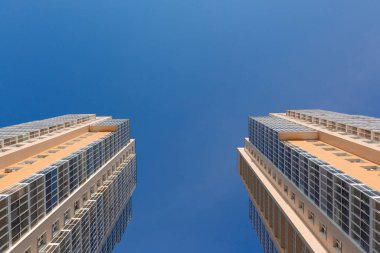 İki kule. Mavi gökyüzünün arka planındaki iki yeni yüksek binanın cepheleri, alt manzara. İnşaat endüstrisi