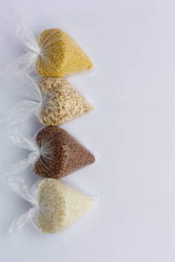 Beyaz arka planda küçük plastik torbalarda çeşitli inlemeler. Pirinç ve yulaf ezmesi, karabuğday ve darı