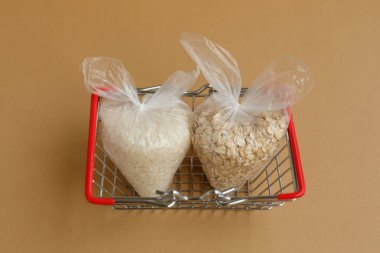 Kahverengi bir arka planda market sepeti içinde paketler halinde çeşitli Groats çeşitleri. Pirinç ve yulaf ezmesi