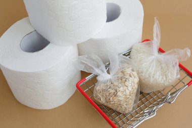 Tuvalet kağıdı ve kahverengi arka planda küçük plastik torbalarda çeşitli tahıllar. Pirinç ve yulaf ezmesi