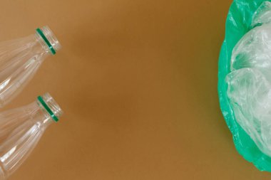 Kahverengi arka planda şeffaf plastik süt şişeleri ve plastik torbalar. Ekoloji ve çöp.
