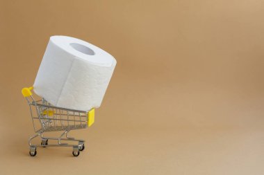 Kolu desenli ya da delikli beyaz tuvalet kağıdı rulosu ve kahverengi arka planda bir market arabası.