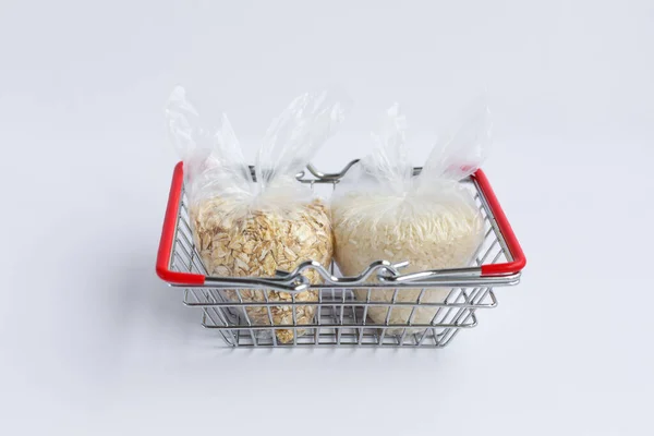 various groats in packages in a grocery basket on a white background. Rice and oatmeal