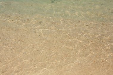 Doğal doku ve arka plan. Suyun üzerinde güneş ışığı ve parlıyor. Denizin sarı kumlu tabanı