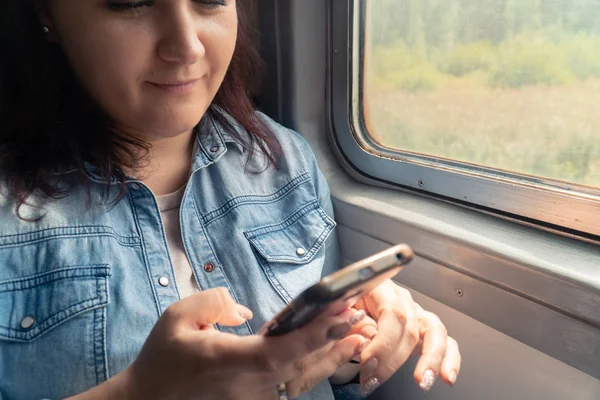 Joven hermosa chica caucásica utiliza un teléfono inteligente en el transporte público durante el viaje — Foto de Stock