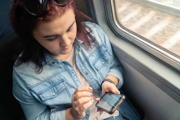 Joven hermosa chica caucásica utiliza un teléfono inteligente en el transporte público durante el viaje — Foto de Stock