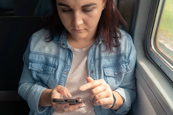 Joven hermosa chica caucásica utiliza un teléfono inteligente en el transporte público durante el viaje — Foto de Stock