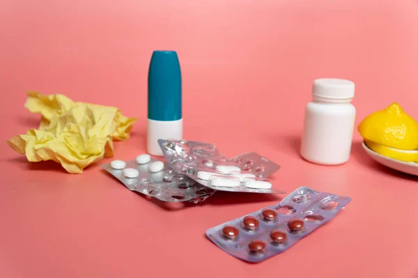 Koncepcja zimna: plasterki cytryny z tabletkami na przeziębienie i aerozol do nosa na różowym tle — Zdjęcie stockowe