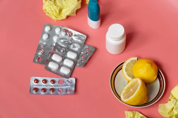 Soğuk algınlığı konsepti: soğuk haplı dilimlenmiş limon ve pembe arka planda burun spreyi.