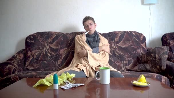 Sick Caucasian Man Sits Couch Blanket Measures His Temperature — Stock Video