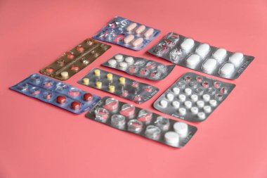 Pembe arka planda tabletleri olan farklı kabarcıklar paketleri