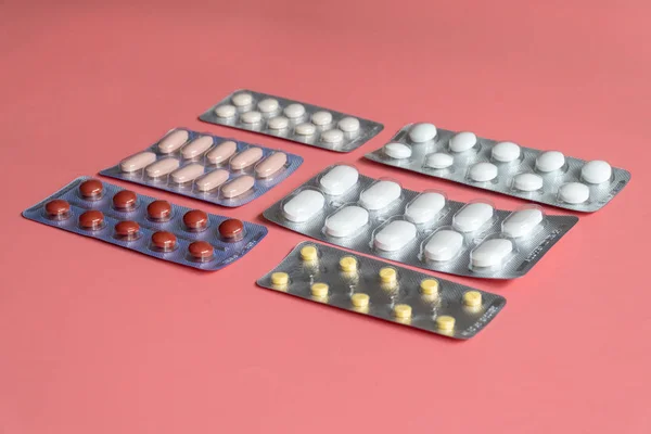 Różne blistry z tabletkami na różowym tle — Zdjęcie stockowe