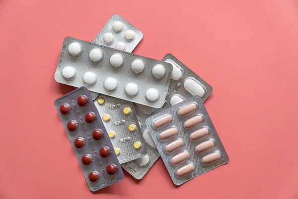 Diferentes blisterspackages com comprimidos sobre fundo rosa — Fotografia de Stock