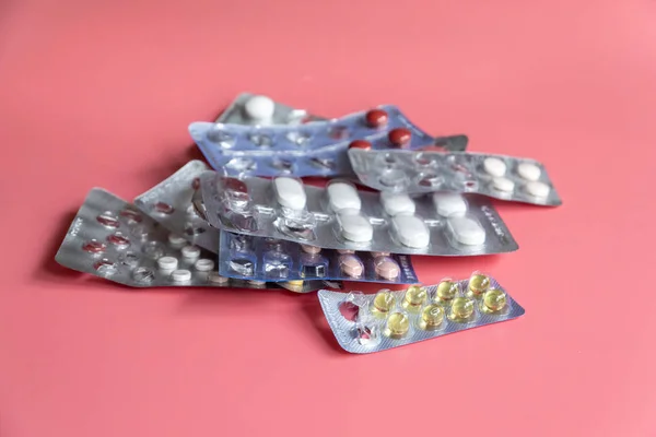 Pembe arka planda tabletleri olan farklı kabarcıklar paketleri