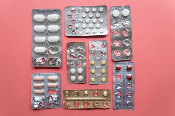 Różne blistry z tabletkami na różowym tle — Zdjęcie stockowe