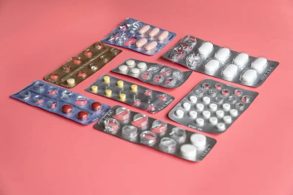 Pembe arka planda tabletleri olan farklı kabarcıklar paketleri