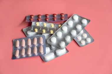 Pembe arka planda tabletleri olan farklı kabarcıklar paketleri