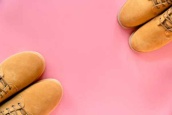 Twee paar gele winterlaarzen op roze achtergrond met een kopieerruimte op het midden Stockafbeelding