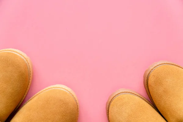 Pembe arka planda iki çift sarı kış botu ve fotokopi alanı