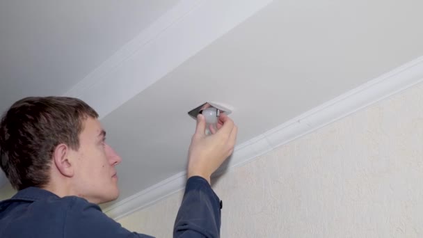 Elettricista avvitato una nuova lampadina nella lampada a soffitto — Video Stock