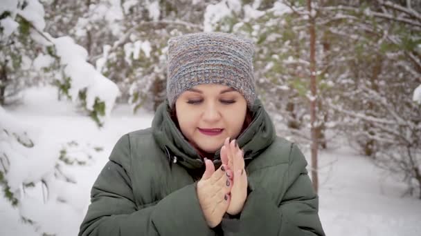 Kaukázusi lány a téli erdőben lélegzettel melegíti a kezét. — Stock videók