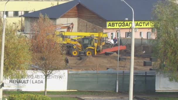 Bobruisk, Belarus - 08 november 2019: Jcb graafmachine rijdt met opgeheven emmer door bouwplaats en transporteert land — Stockvideo