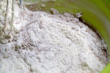 Kadınların elleri plastik kasede çırpıyla hamuru kırbaçlıyor.