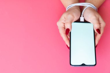 Top view woman hands have a modern smartphone whith blank screen on pink background. Addiction on social networking sites, internet and gadgets .