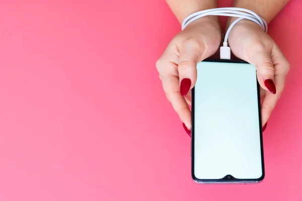 Top view woman hands have a modern smartphone whith blank screen on pink background. Addiction on social networking sites, internet and gadgets .