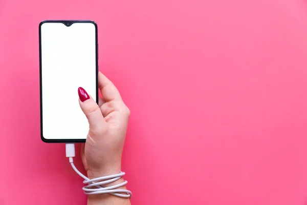 Close up woman hand are having a modern smartphone whith blank screen on pink background. Dependences on social networking sites, internet and gadgets . — 스톡 사진