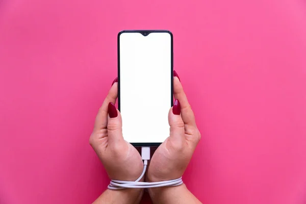 Pembe arka planda modern bir akıllı telefon olan kadın ellerini kapat. Sosyal ağ sitelerine, internete ve aygıtlara bağımlılık .