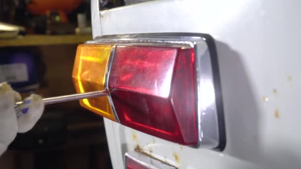 Mecánico de coche quita la luz trasera de un coche viejo — Vídeo de stock