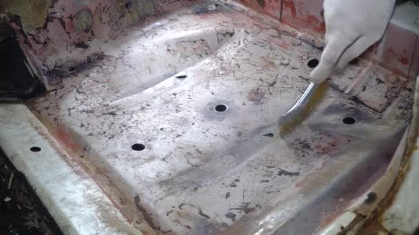Mecânico de carro limpa o chão do carro com uma escova de metal da ferrugem — Vídeo de Stock