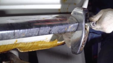 Otomatik tamirci vidaları söküp arkadan krom tamponu takıyor.