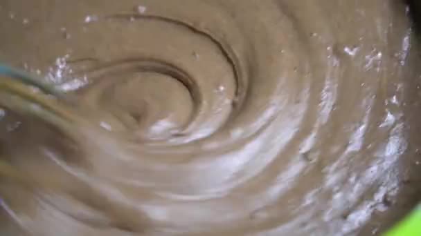Close-up pasteleiro chef amassa massa com batedor de chocolate em tigela verde — Vídeo de Stock