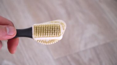 Adam fırçaya ayakkabı temizleme köpüğü koyar.