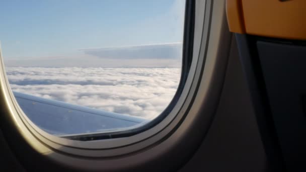 Vista da janela da aeronave sobre as nuvens iluminadas pela luz solar — Vídeo de Stock