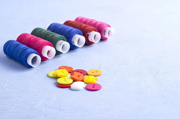 Multicolored sewing threads on a blue background. Concept of needlework, manual labor, sewing.