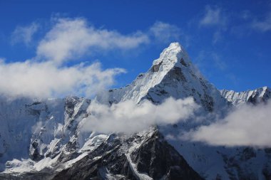 Peak of Mt Ama Dablam surrounded by clouds clipart