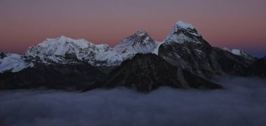 Pink evening sky over mount Everest and Cholatse. Sea of fog. clipart