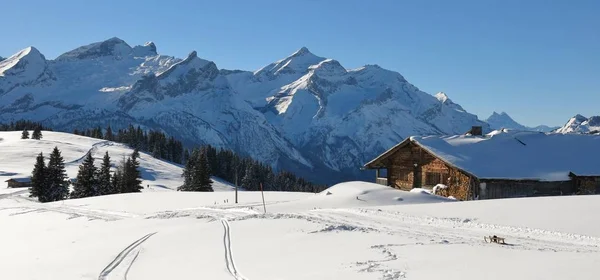Gamla timmerkoja och snö täckta bergskedja. Bergen Schlau — Stockfoto