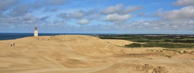 Deniz feneri altında büyük bir kumul yavaş yavaş kayboluyor. Mavi deniz bir
